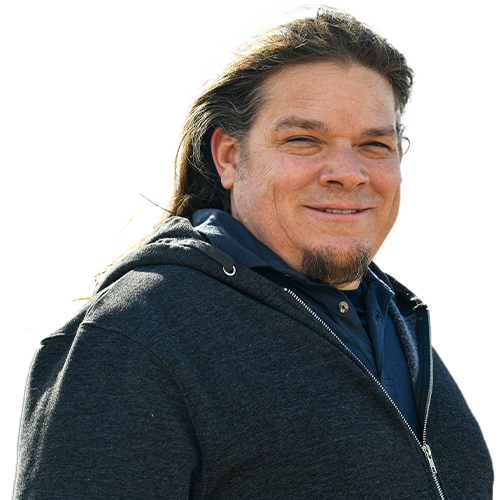 Warrior Joseph Pierstorff smiles, wearing a black zipped-up hoodie over a navy-blue polo shirt.