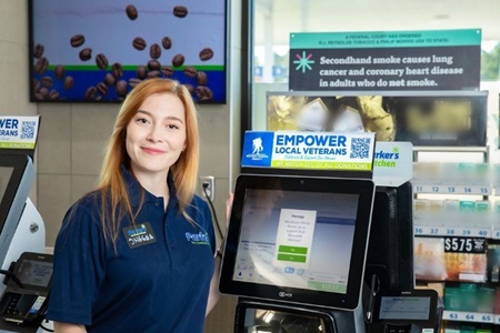 A Parker's Kitchen employee smiles next to a checkout screen showing a donation message for Wounded Warrior Project.