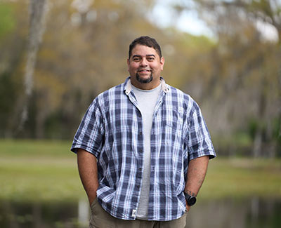 Veteran Tim Aponte stands in the woods.