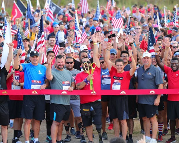 Participants at the 2019 Carry Forward 5K in San Antonio, Texas, cheer while the event ribbon is cut with a large pair of scissors.