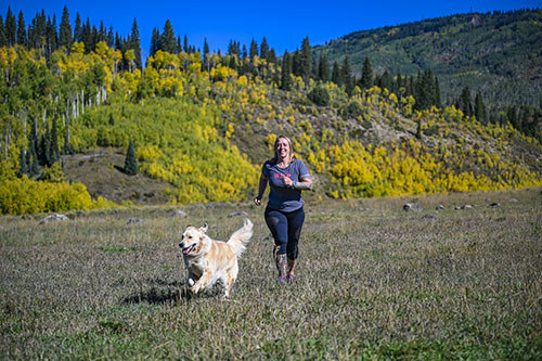 Woman warrior and Army veteran Angie Peacock in a field with her golden retriever.
