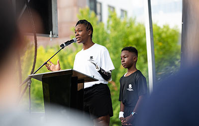 Wounded warrior and Purple Heart recipient Danielle Green shares her story of purpose and service with the crowd at a WWP Carry Forward event. Her son Daniel is by her side.