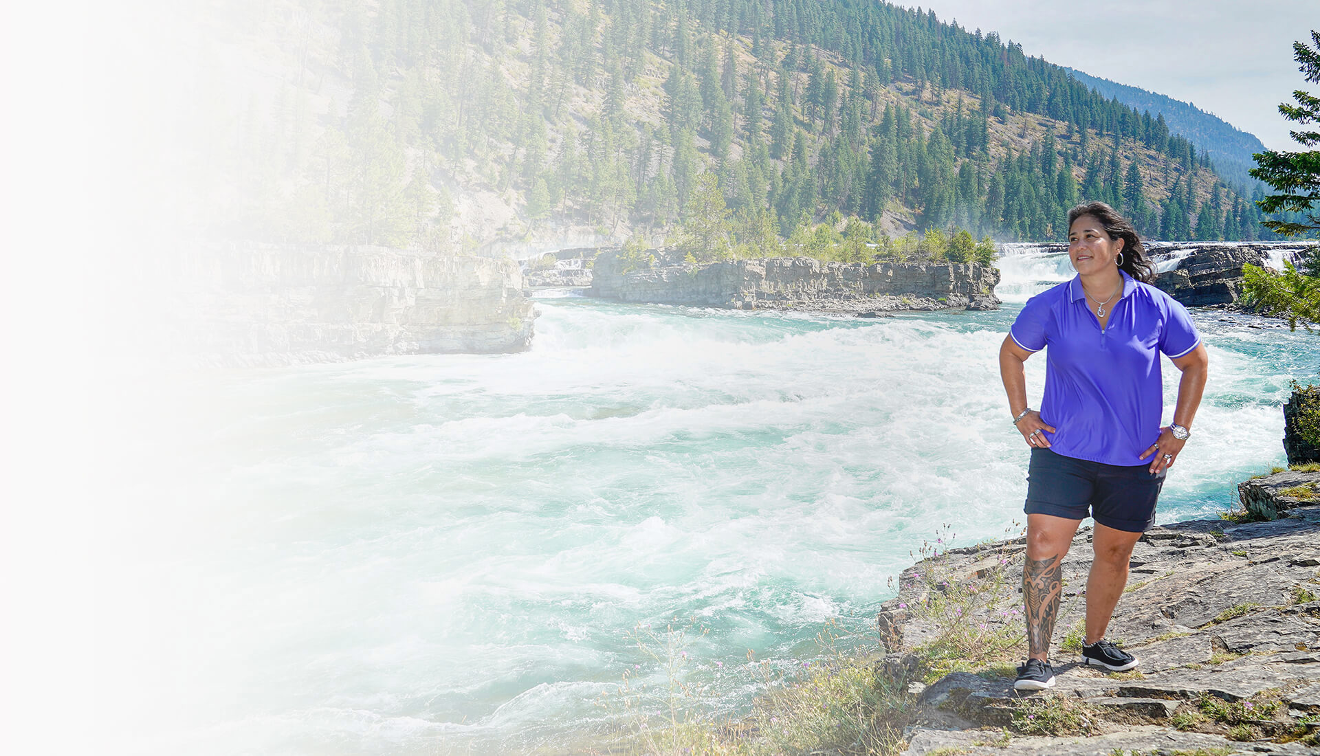 Wounded Warrior Tina Waggener stands in front of a tree-covered mountain and river while gazing at the scenery.