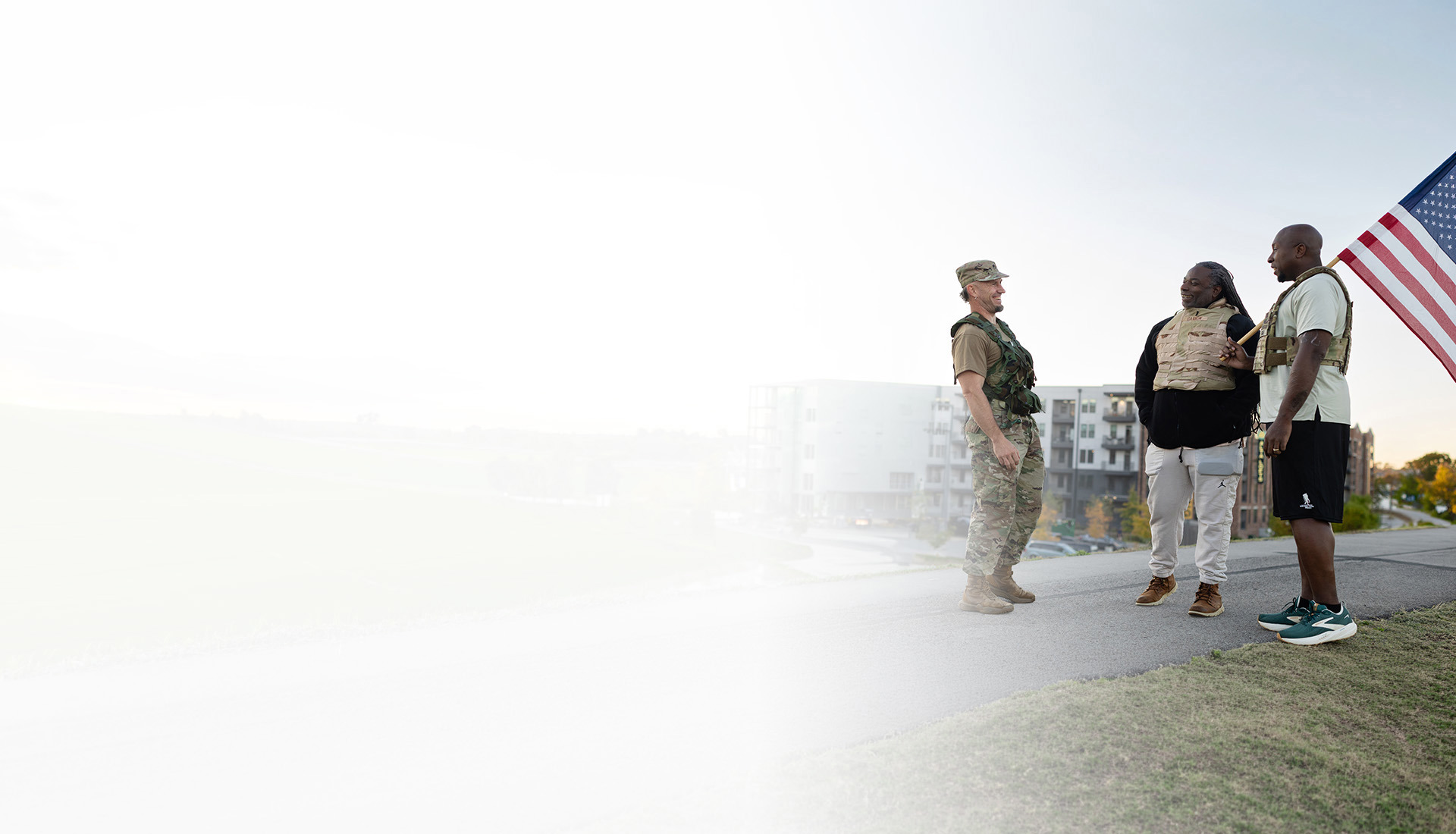 Warriors gather outdoors, connecting in conversation during a community event with a service dog nearby.