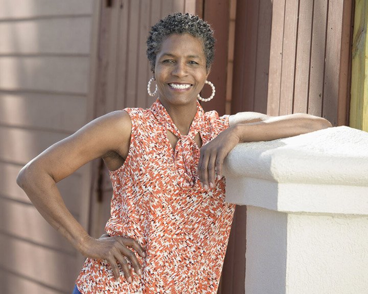 La veterana herida, Tonya Oxendine, posa apoyada contra un poste afuera y sonríe.