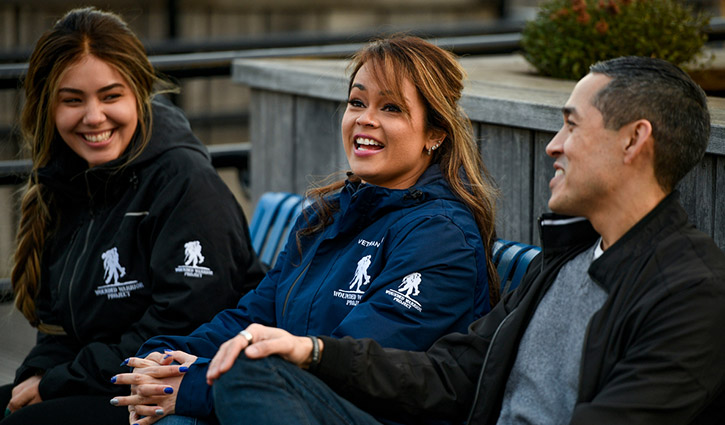 Wounded warriors Rochelle Santiago, Antoinette Wallace and Sergio Alfaro sit on a bench outdoors talking.