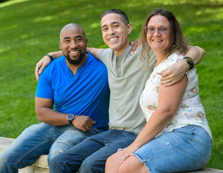 Wounded warriors Michael Powell, Sergio Alfaro, and Nicole Shorter sit atop a brick wall and smile for a group photo.