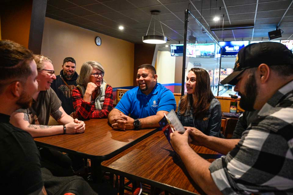 A photo of a group of veterans sitting around a table laughing and talking.