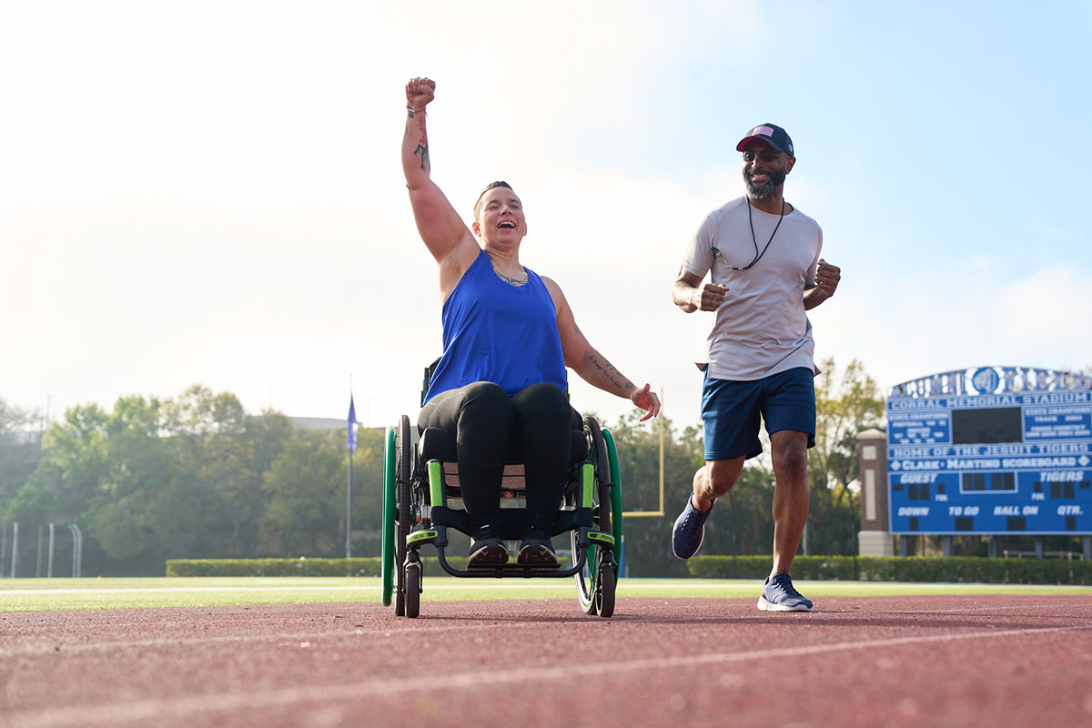 Wounded warrior Beth King and her adaptive sports coach cheering in a track field.