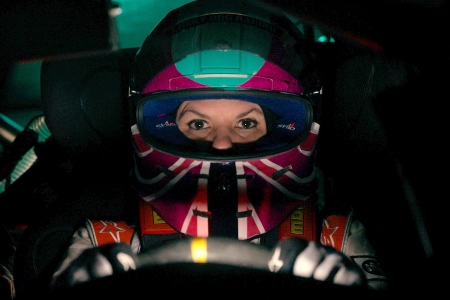 A close up of Melissa facing front behind the wheel of her race car