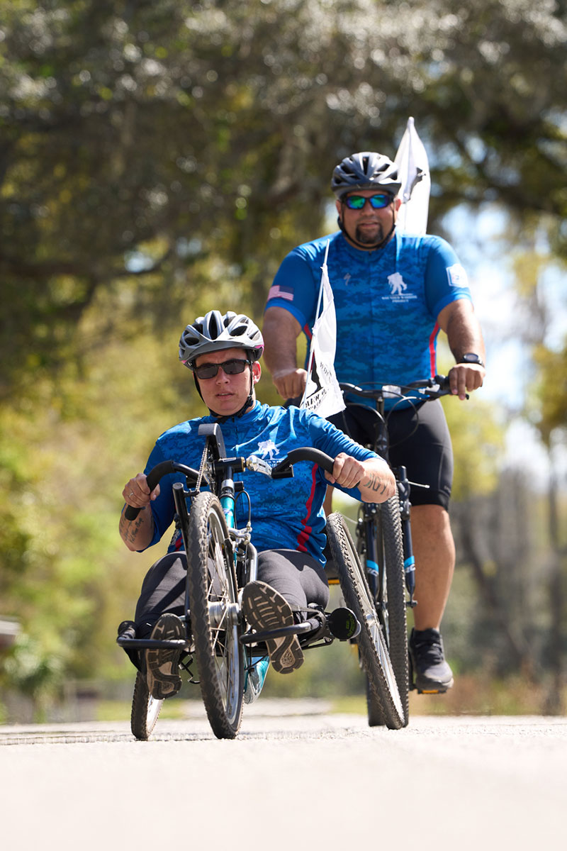 Beth King, veterana herida, con una bicicleta adaptada y el veterano Tim Aponte participando en un evento de Soldier Ride.