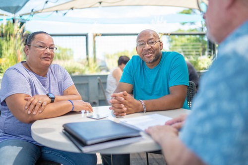 A couple sits across from another person at a table