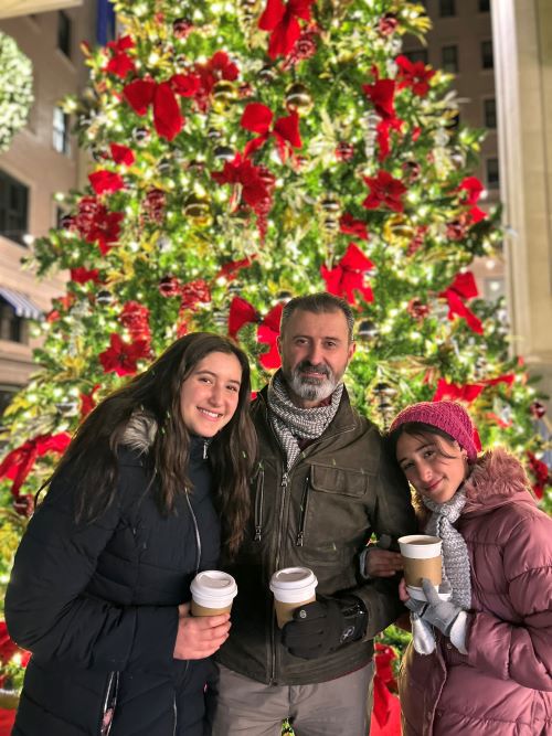  The sisters and their Dad enjoying time in front of a holiday tree – Alt caption goes here