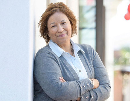 Caregiver Cindy Parsons leans against a wall while smiling and crossing her arms. 