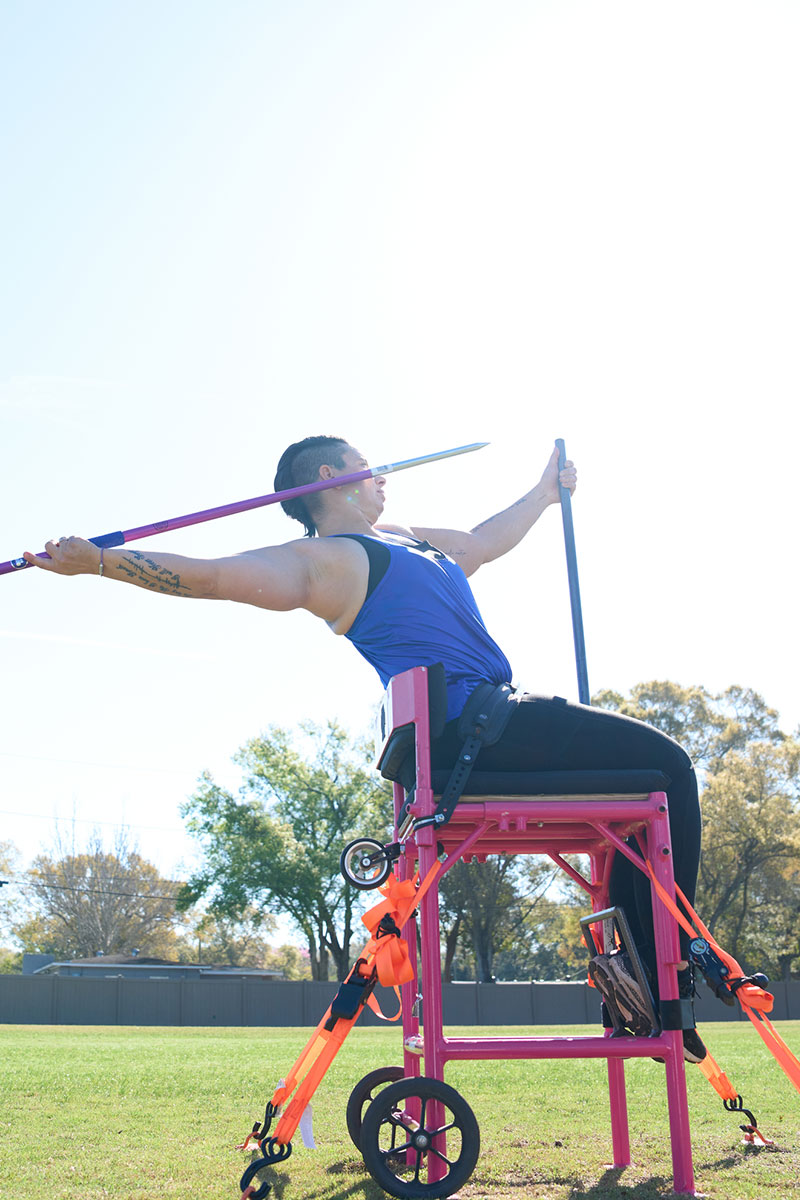 Beth King, veterana herida, lanzando una jabalina desde una silla fija durante un evento de deportes adaptados.