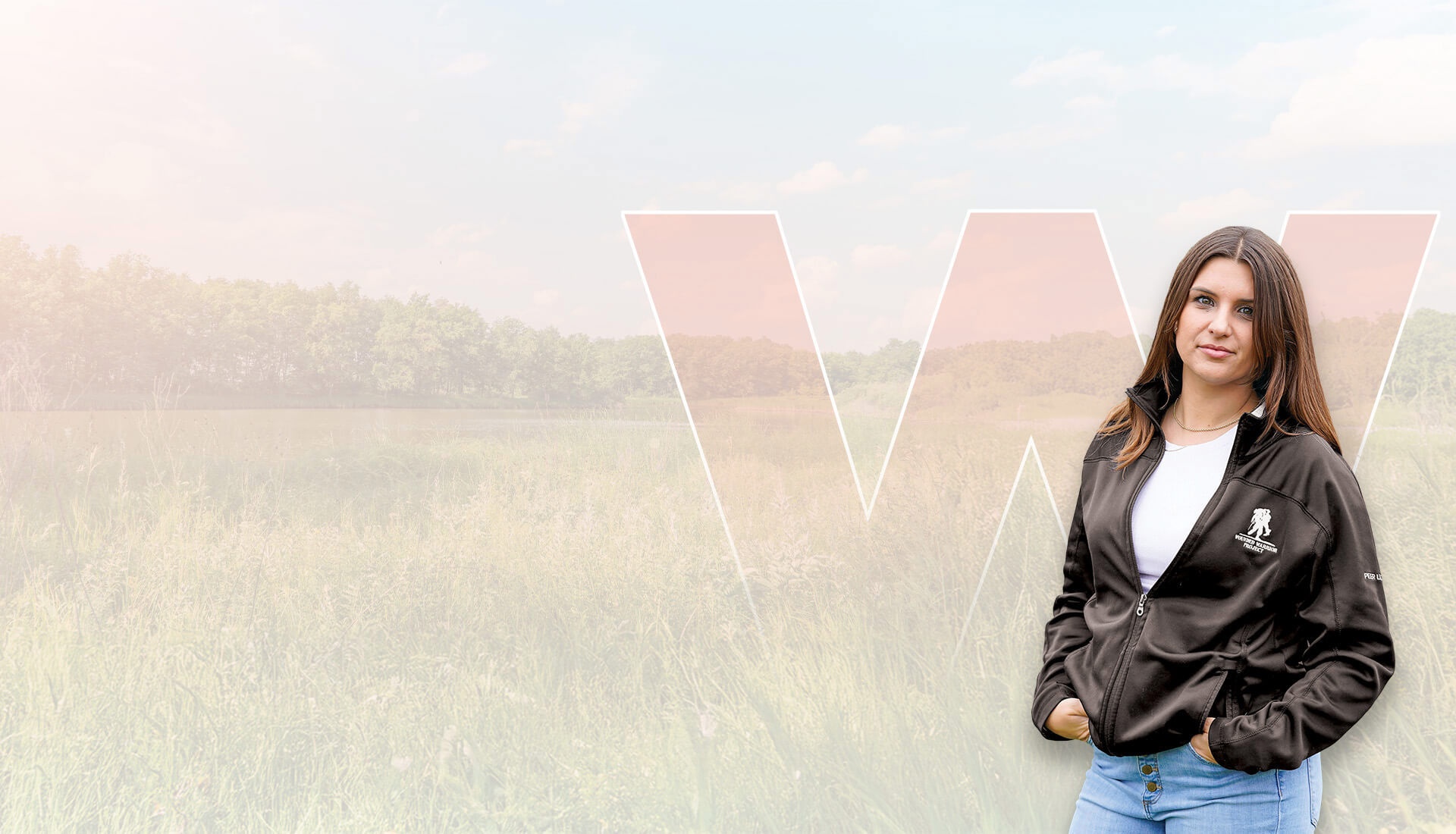 Wounded warrior Keara Torkelson smiling in a field while wearing a black WWP jacket with her hands in the pockets.