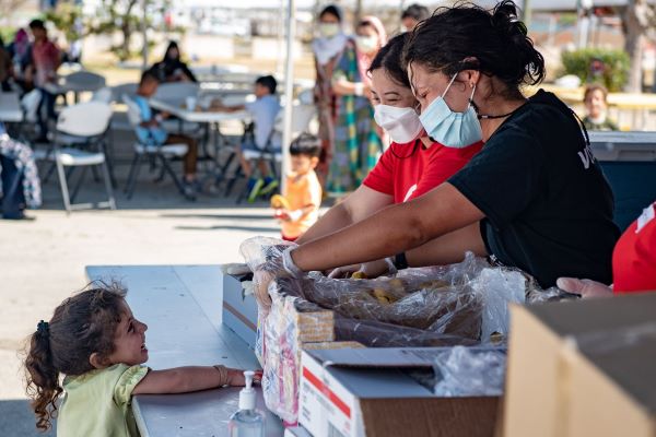 Volunteers share a smile with a laugh with a young girl while handing out supplies