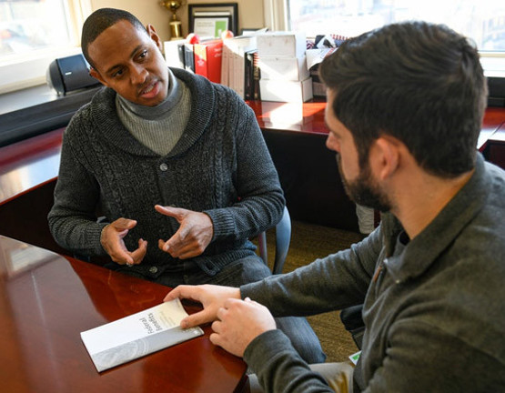 Warrior Tyshawn Jenkins sitting at a desk discussing Financial Wellness with an advisor.