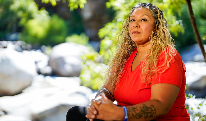 Wounded warrior Ysabel Cardona poses in front of a scenic background while sitting down.