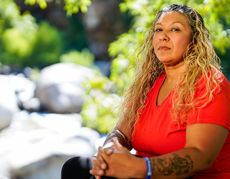 Warrior Ysabel Cardona poses in front of a scenic background while sitting down.