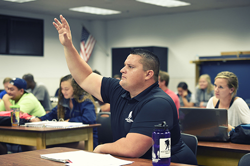 A WWP warrior raises his hand in a classroom environment.