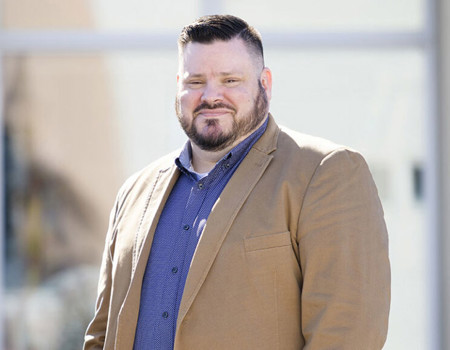 Wounded Warrior Jake Norotsky stands outside while smiling. 