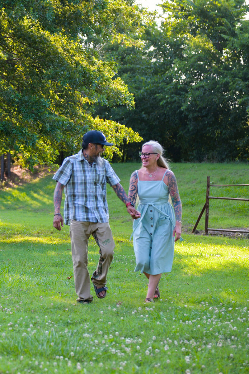 Wounded Warrior Ray Andalio and his wife, Deedra, walking while holding hands in a field of flowers and smiling.