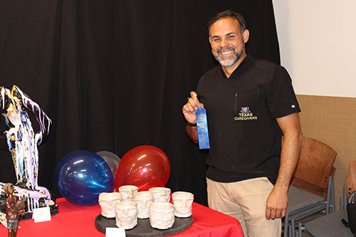WWP warrior Eli posing with a blue, first-place ribbon for sculpting at an event.
