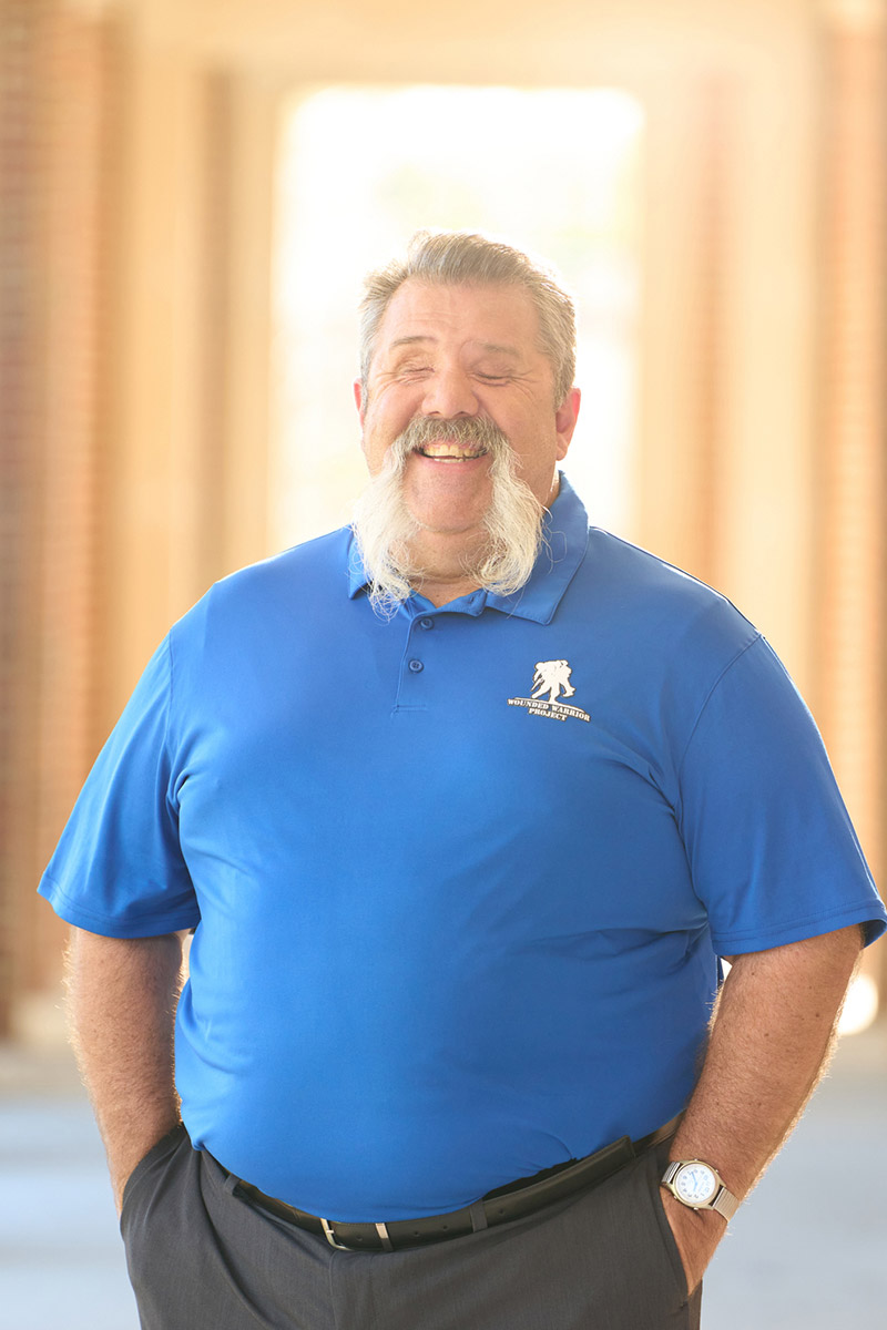 Aaron Cornelius, veterano herido, luce un polo azul de WWP y sonríe.