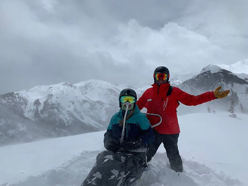 WWP warrior Mary Porter sits in a sled on top of a snowy mountain at the Invictus Games.