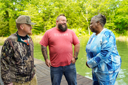Three veterans talking together outside near some water