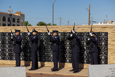 A police honor guard shoots rifles in a funeral salute.