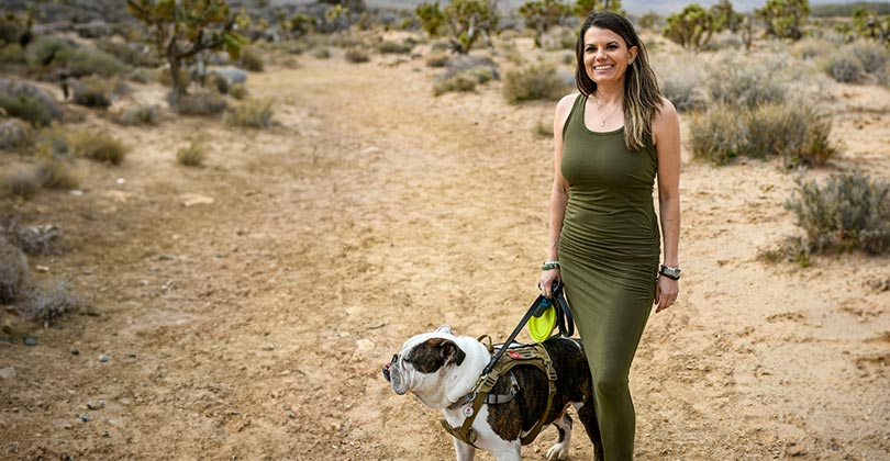 Wounded warrior Melissa McMahon standing outdoors holding her dog.