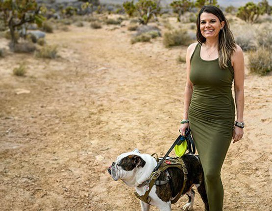 Wounded warrior Melissa McMahon standing outdoors holding her dog.