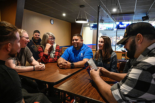 A group of veterans talk and laugh at a table.