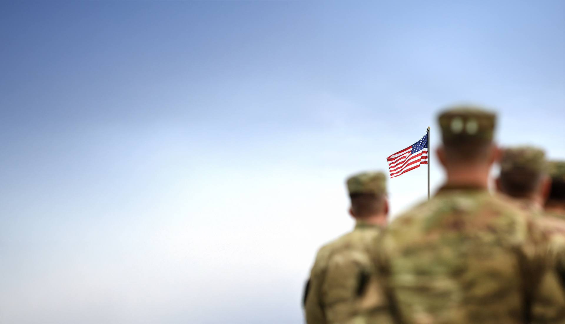 Soldiers standing together looking at the American Flag.