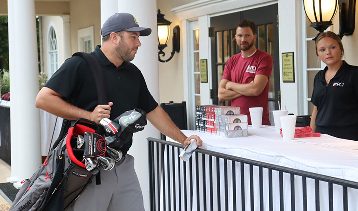 A person standing next to a table with a golf bag during the PCI Golf Fundraiser