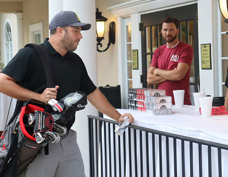 A person standing next to a table with a golf bag during the PCI Golf Fundraiser